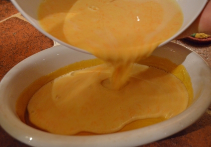 Pouring the pumpkin flan into the prepared dish